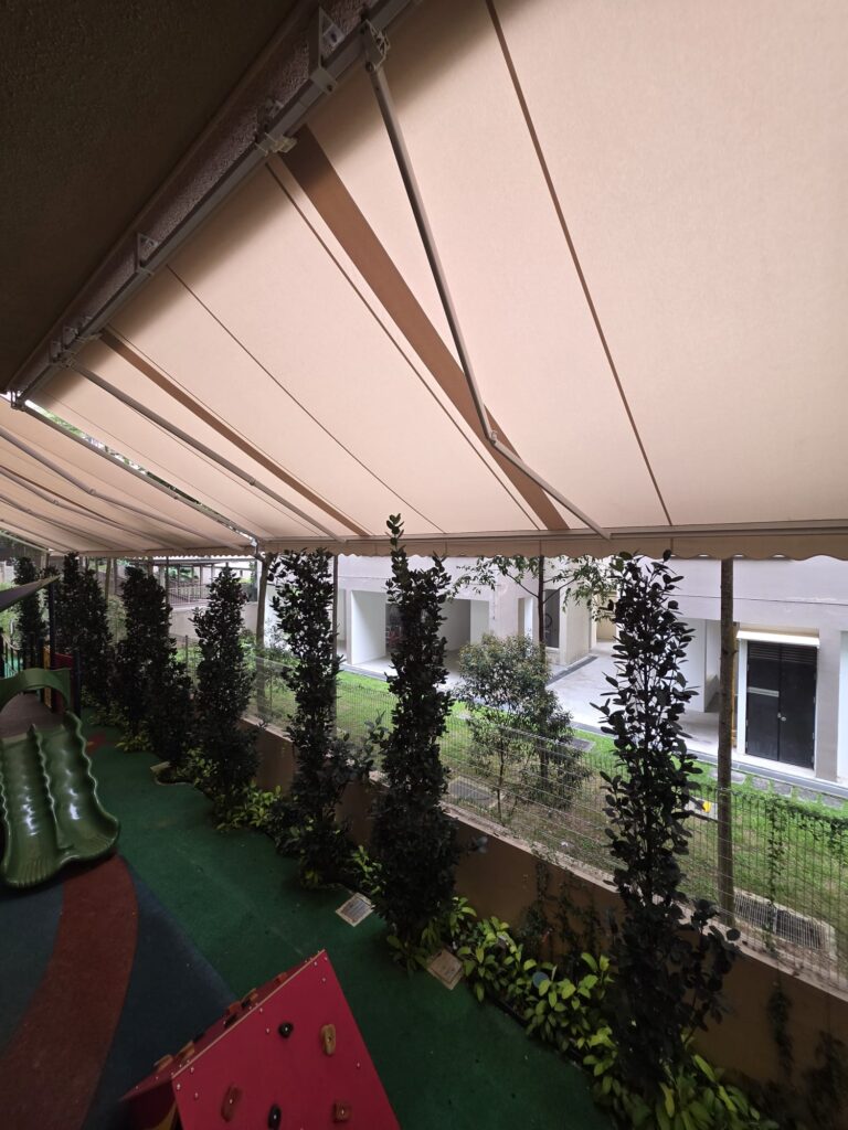 Beige retractable awning extending over a colourful outdoor playground walkway