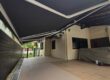 Black retractable awnings providing shade over a spacious residential car porch