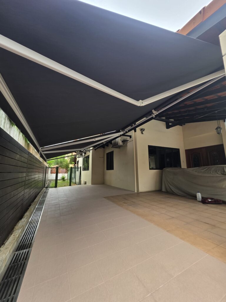 Black retractable awnings providing shade over a spacious residential car porch