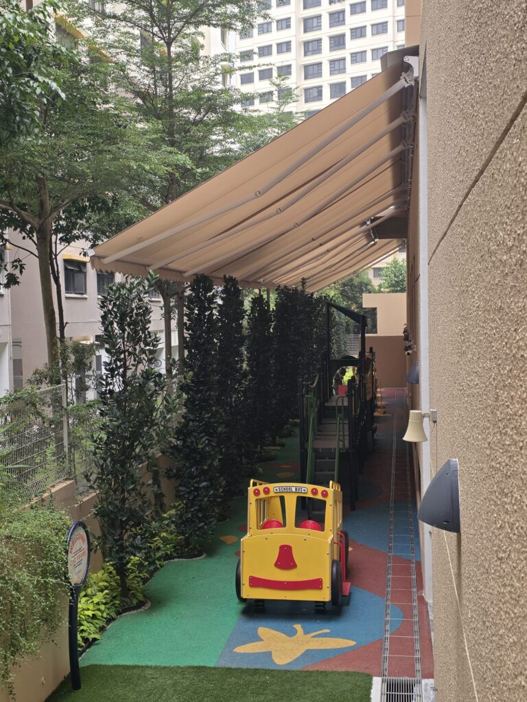 Beige retractable awnings installed above an outdoor children's playground in Singapore