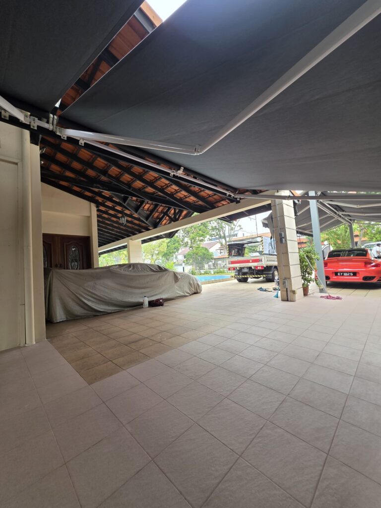 Black retractable awnings extending beneath the tiled roof of a residential car porch
